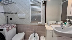 A bathroom with a toilet, bidet, sink, and a towel rack. - Casa Ariel in the historic village. (Rio dell'Elba)