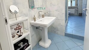 A bathroom with a white sink, mirror, and shelves with toiletries.