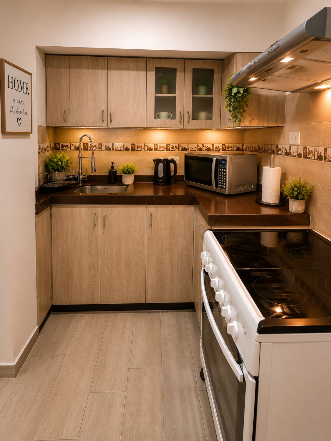Una cocina moderna con armarios de madera, estufa de acero inoxidable, microondas y pileta.