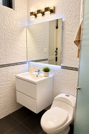 A modern bathroom with a white vanity, a toilet, and a mirror above the sink.
