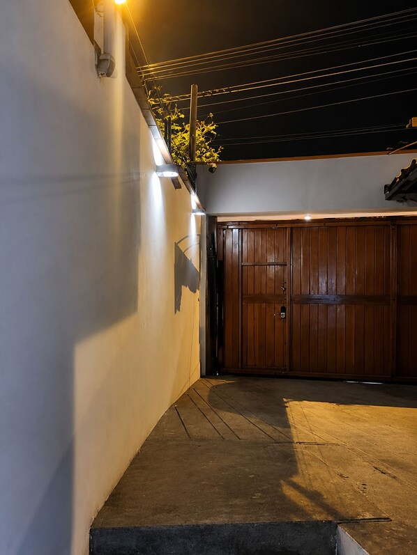 A garage with a wooden door, a concrete floor, and a wall with a light fixture.
