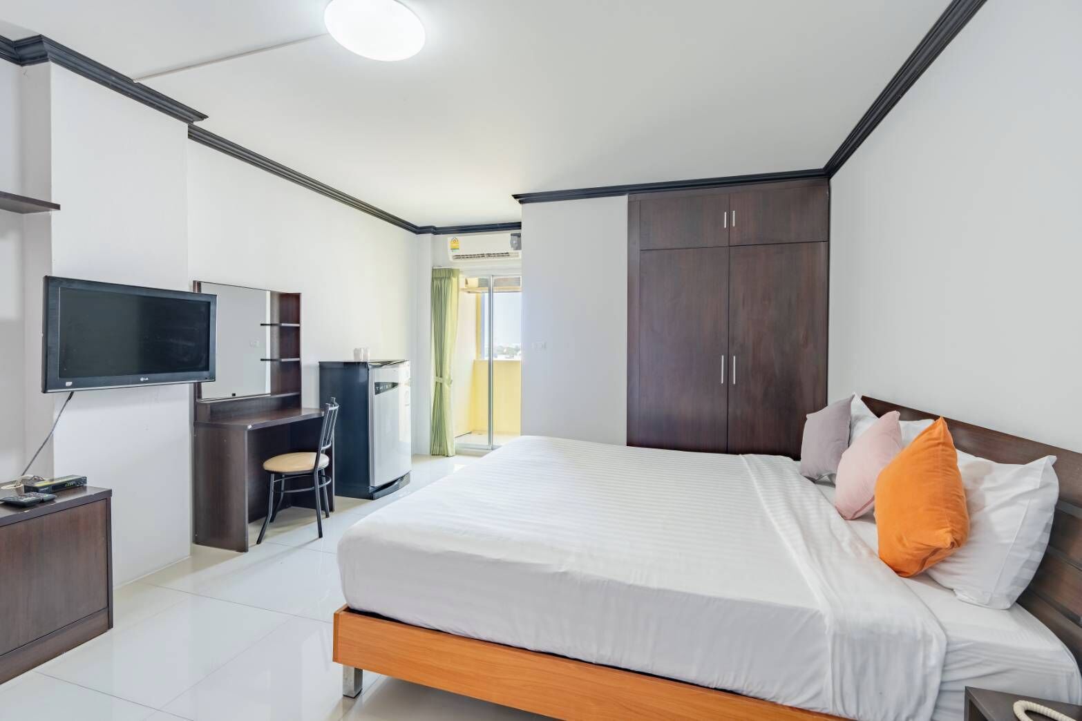 Una habitación de hotel moderna con cama, escritorio, televisión y armario.