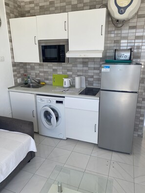 Une cuisine compacte équipée d’un lave-linge, d’un réfrigérateur, d’un four à micro-ondes et d’un évier.