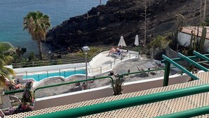 Une vue sur la côte, avec un paysage rocheux, une piscine et quelques personnes qui se détendent.