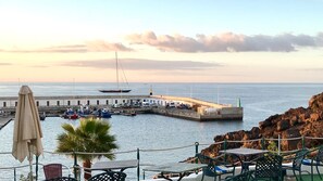 Un port de plaisance situé sur la côte, avec des bateaux, une jetée et une rive rocheuse.