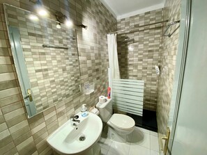 Une salle de bain avec un lavabo, des toilettes et une douche.