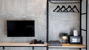 Een moderne kamer met een flatscreen televisie, een bureau met telefoon, een lamp en een kluis.