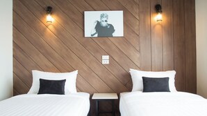 Een hotelkamer met twee bedden, een houten wand en twee wandlampen.