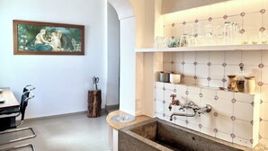 Una cocina moderna con un lavamanos integrado, salpicadero de azulejos blancos y una mesa de comedor de madera con sillas.