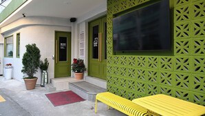 Een hotelentree met groene deuren, een receptiebalie, een bank en potplanten.