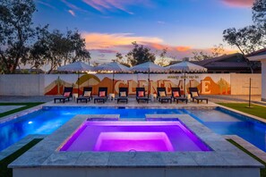 A swimming pool with lounge chairs and umbrellas, surrounded by a wall with a desert-themed mural.