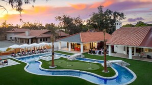 Un resort con piscina, zona de estar al aire libre y vistas al atardecer.