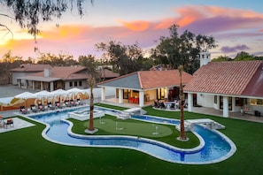 A resort with a swimming pool, outdoor seating, and a view of the sunset.