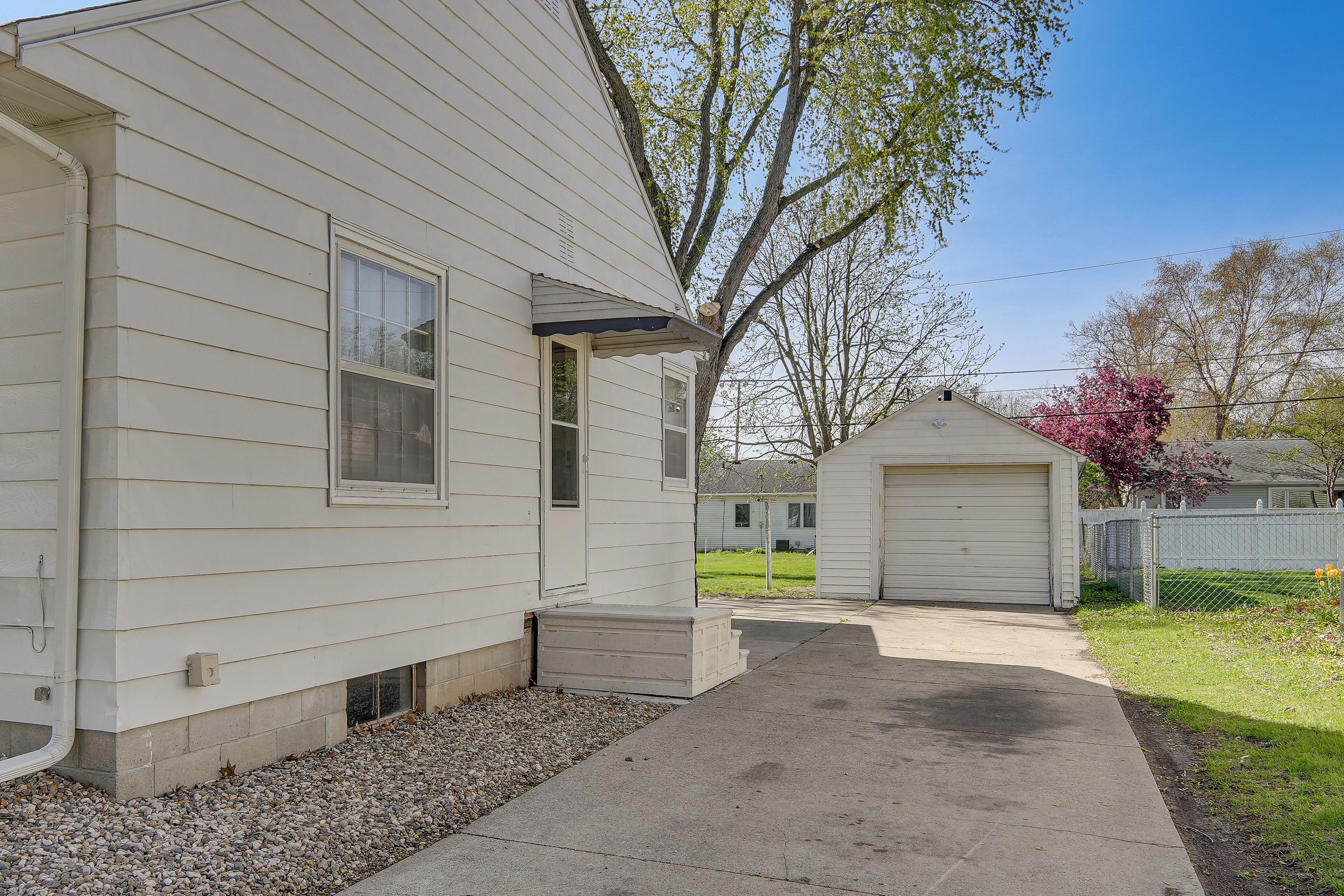 A single-story house with a garage, a covered porch, and a gravel driveway.