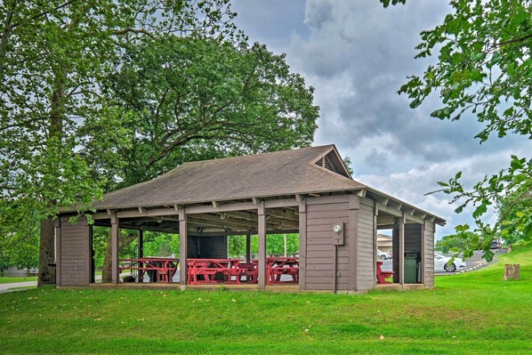Un pavillon abrité, doté de tables de pique-nique, entouré de pelouse et d’arbres.