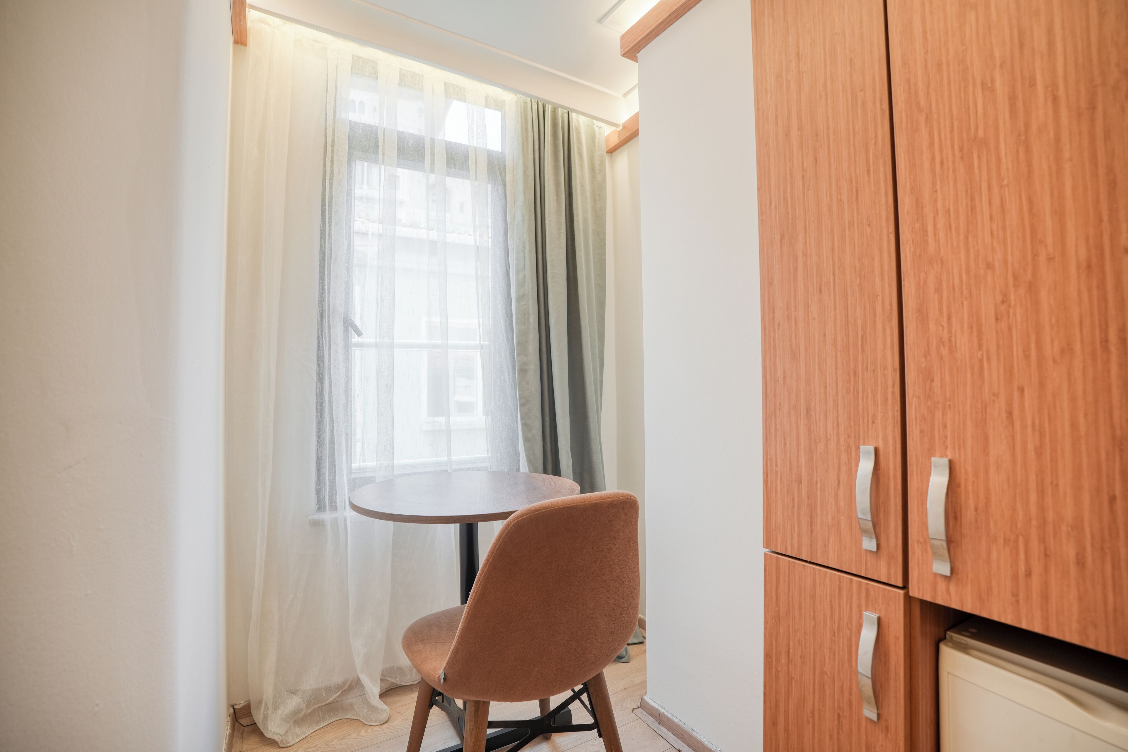 A room with a round table, a single chair, and a wooden cabinet with two doors.