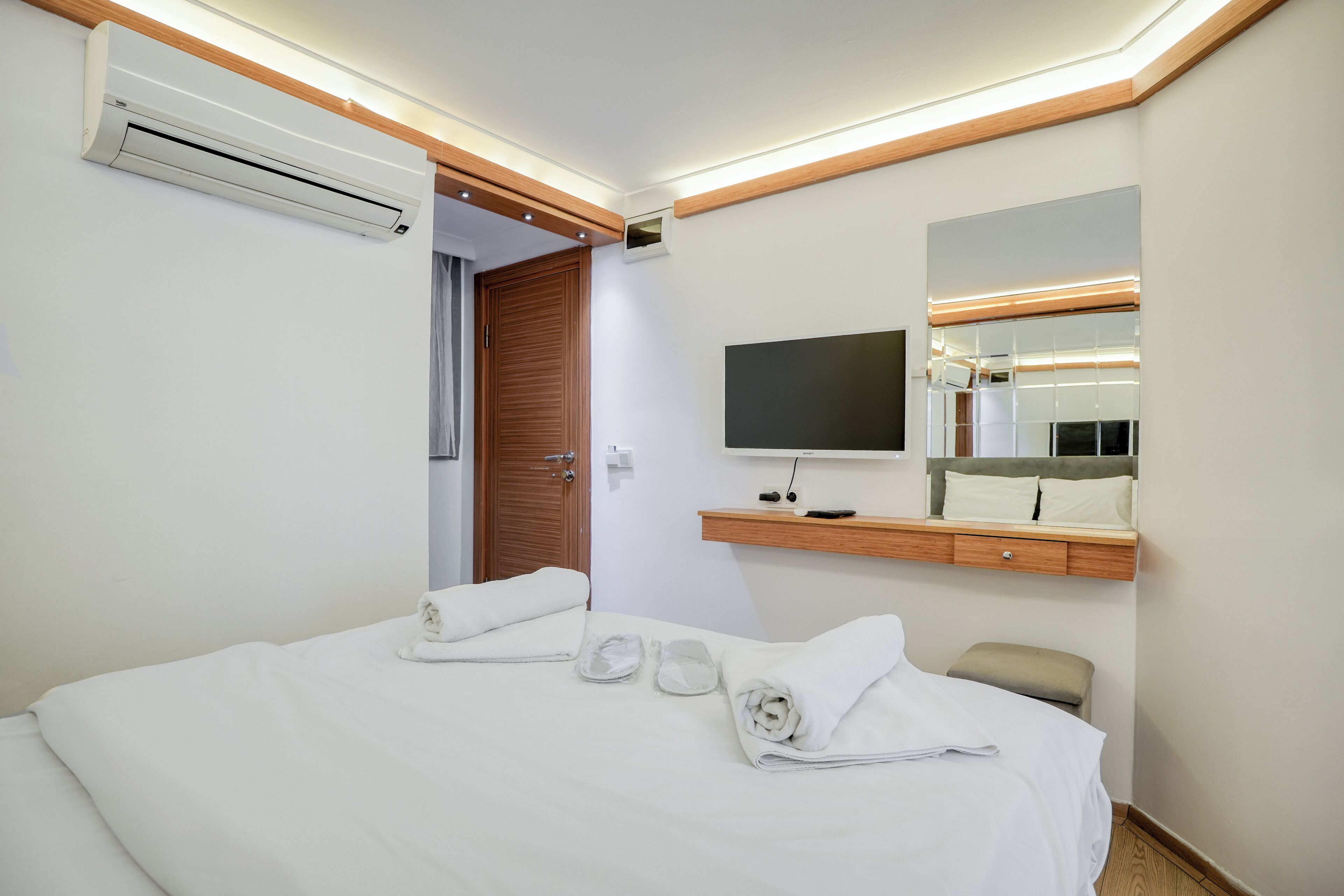 Una camera d'albergo con un letto, una televisione, uno specchio e un condizionatore d'aria.