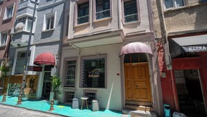 A building with a wooden door, a window with a sign, and a small outdoor seating area with a table and chairs. - Viva Sirkeci Butik Otel (Istanbul)