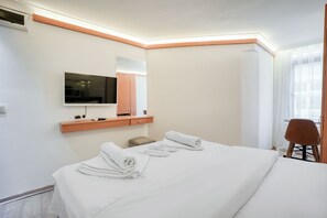 A hotel room with a bed, a TV mounted on the wall, a wooden shelf, and a chair. - Viva Sirkeci Butik Otel (Istanbul)