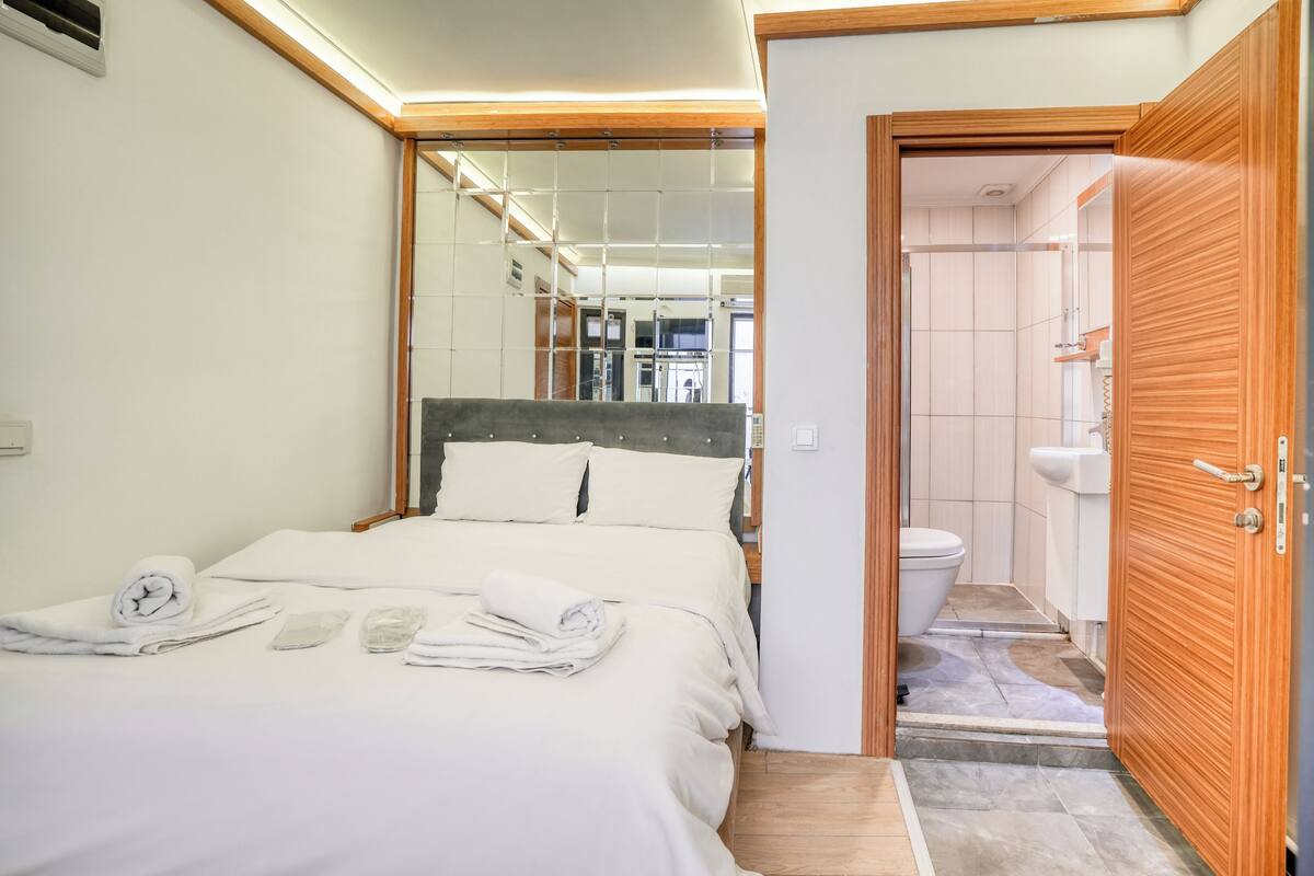 Una camera d'albergo con un letto, un bagno e una porta in legno.