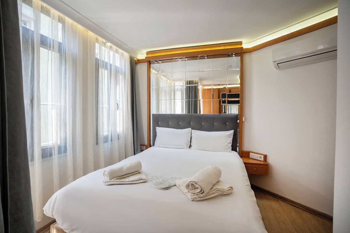 Una camera d'albergo con un letto grande, una testiera in legno, un comodino e un condizionatore.