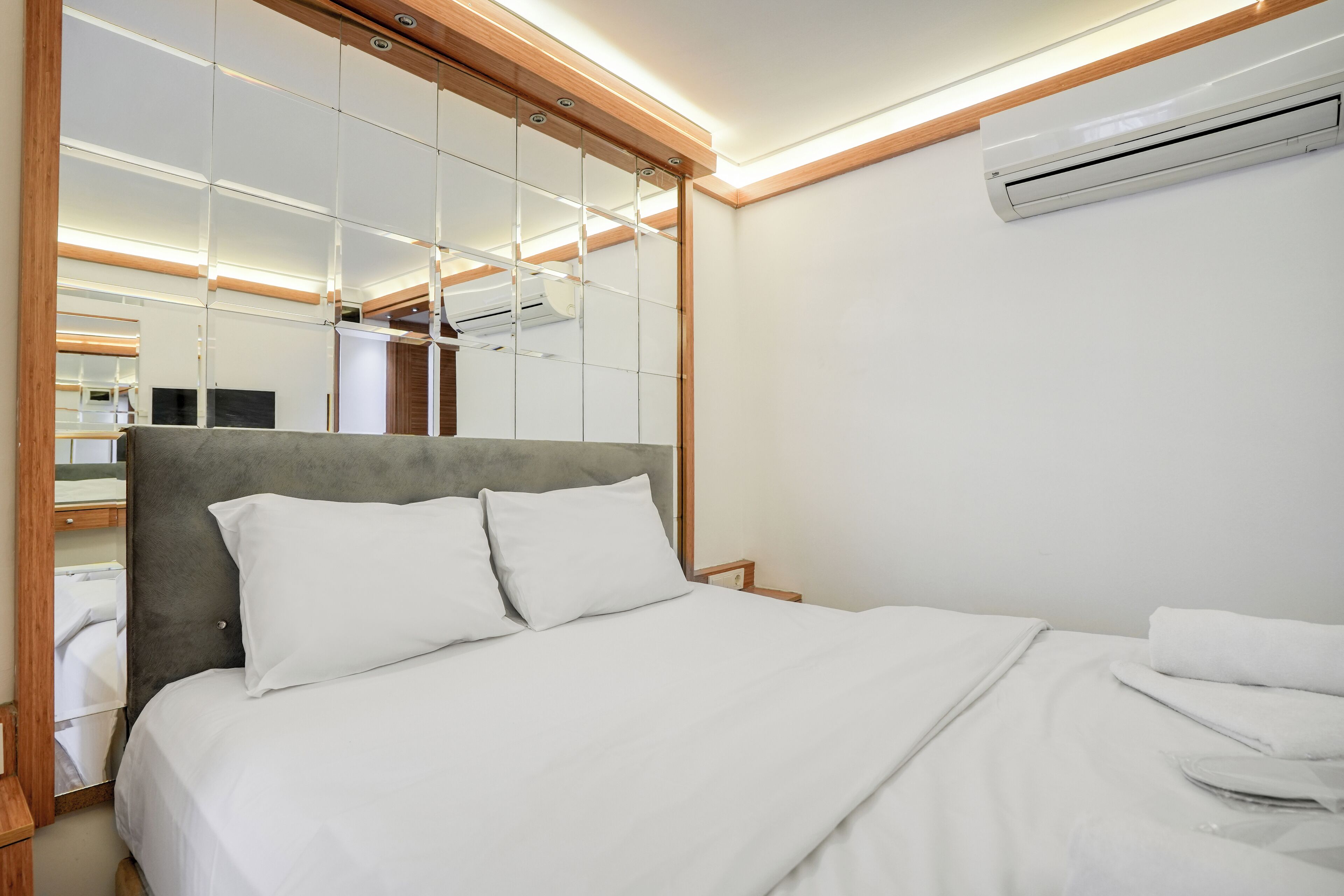Una habitación de hotel moderna con una cama grande, cabecero de madera y aire acondicionado integrado.