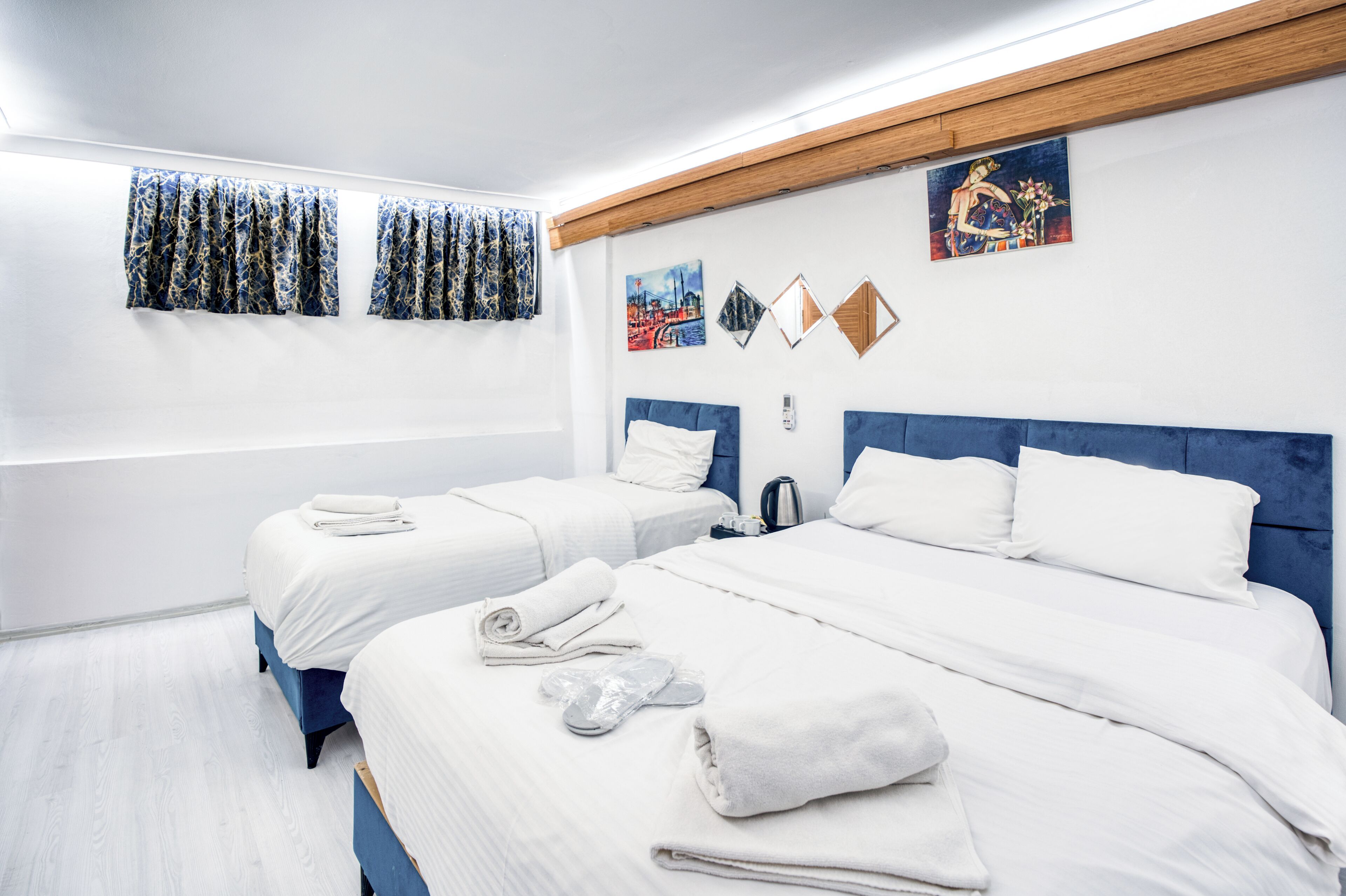 Une chambre d’hôtel avec deux lits, une baignoire et des œuvres d’art aux murs.