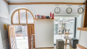 A hotel lobby with a wooden door, a glass door leading outside, a shelf with books and flags, and clocks showing Tokyo, London, and Paris times. - Viva Sirkeci Butik Otel (Istanbul)