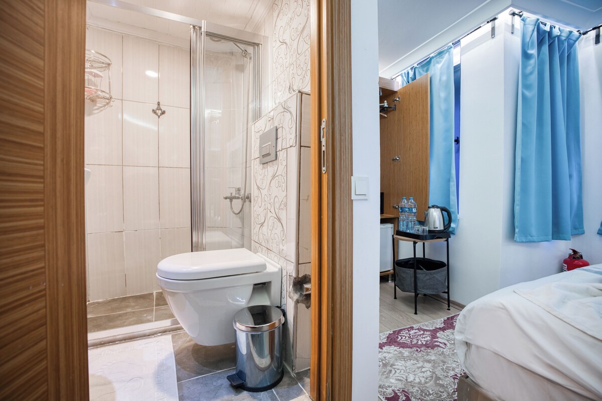 A modern bathroom with a shower, toilet, and a small table with a kettle.