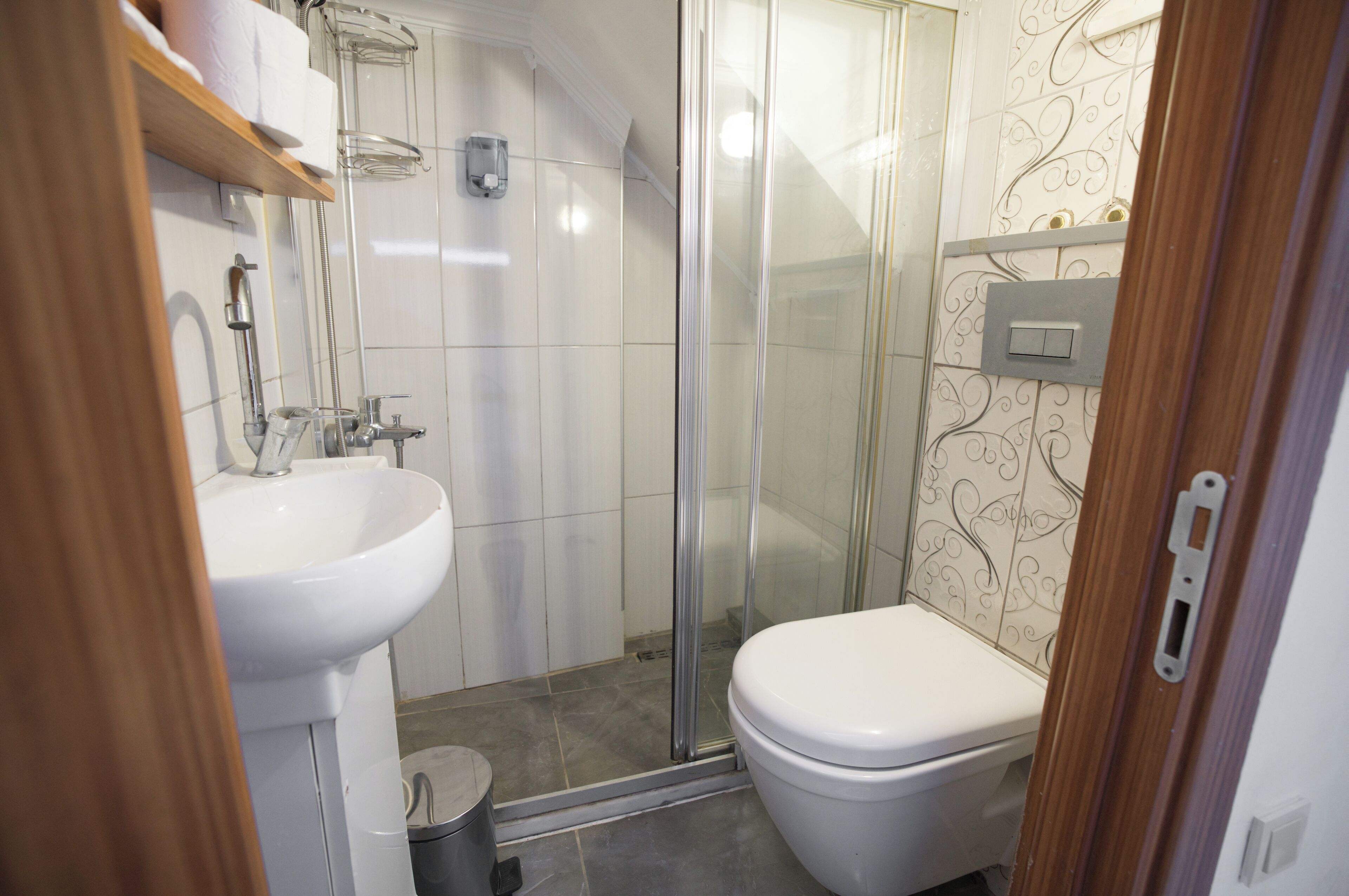 A bathroom with a white sink, toilet, and glass shower enclosure.