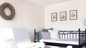 Een slaapkamer met een bed, een bureau en een stoel. Aan de muur hangt een krans en er zijn drie ingelijste foto's.