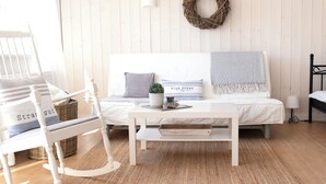 Een gezellige slaapkamer met een bed, een schommelstoel, een nachtkastje en een wandlamp.