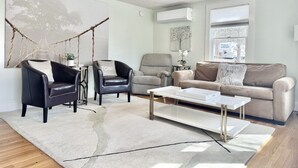 Un salon moderne avec un canapé, deux fauteuils, une table basse et une plante suspendue.