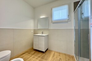 A bathroom with a toilet, a sink, a mirror, and a shower. - Appartamento J Eight 4 - Carraro Immobiliare Jesolo (Lido di Jesolo)