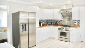 A modern kitchen with white cabinets, stainless steel appliances, and a tiled backsplash. - Spacious Stay Near Carowinds Amusement Park | Newly Remodeled | Fenced Yard | Pet & Family Friendly (Pineville)