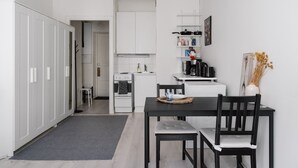 A compact kitchen with white cabinets, a stove, and a dining area with a table and chairs.