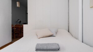 Une chambre à coucher au style minimaliste, avec un lit, une serviette pliée et un luminaire suspendu.