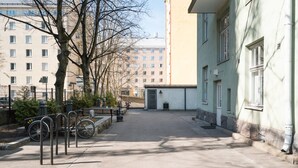 Une rue tranquille en ville, bordée de vélos garés, un immeuble à la façade bleu clair et un ciel dégagé.