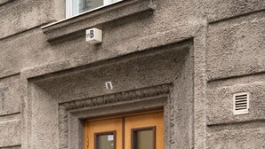 A building facade with a double wooden door, a small window above the door, and a mailbox on the wall. - Renovated Top Floor Studio in Kallio (Helsinki)