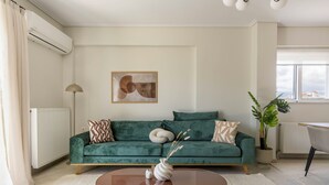 A modern living room with a teal sofa, a round coffee table, and a minimalist decor. - Refined 2BR Apartment in Marousi (Marousi)