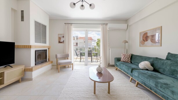 A modern living room with a flat-screen TV, a fireplace, a sofa, and a dining area with a table and chairs. - Refined 2BR Apartment in Marousi (Marousi)