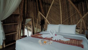 Una cama con sábanas blancas, una toalla dispuesta en forma de corazón y una flor decorativa.