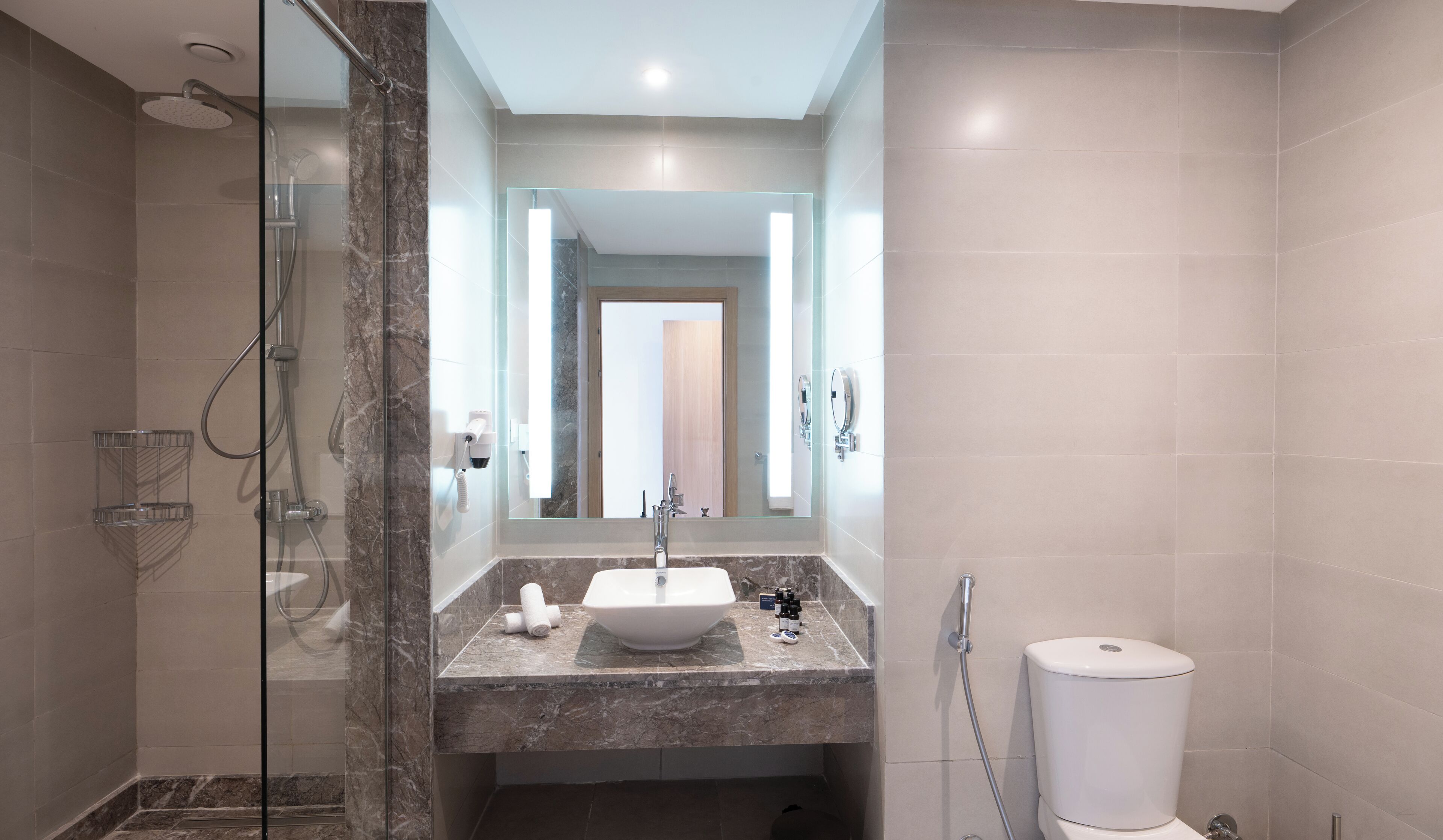 Une salle de bain moderne avec une douche à parois de verre, un lavabo en marbre et des toilettes.