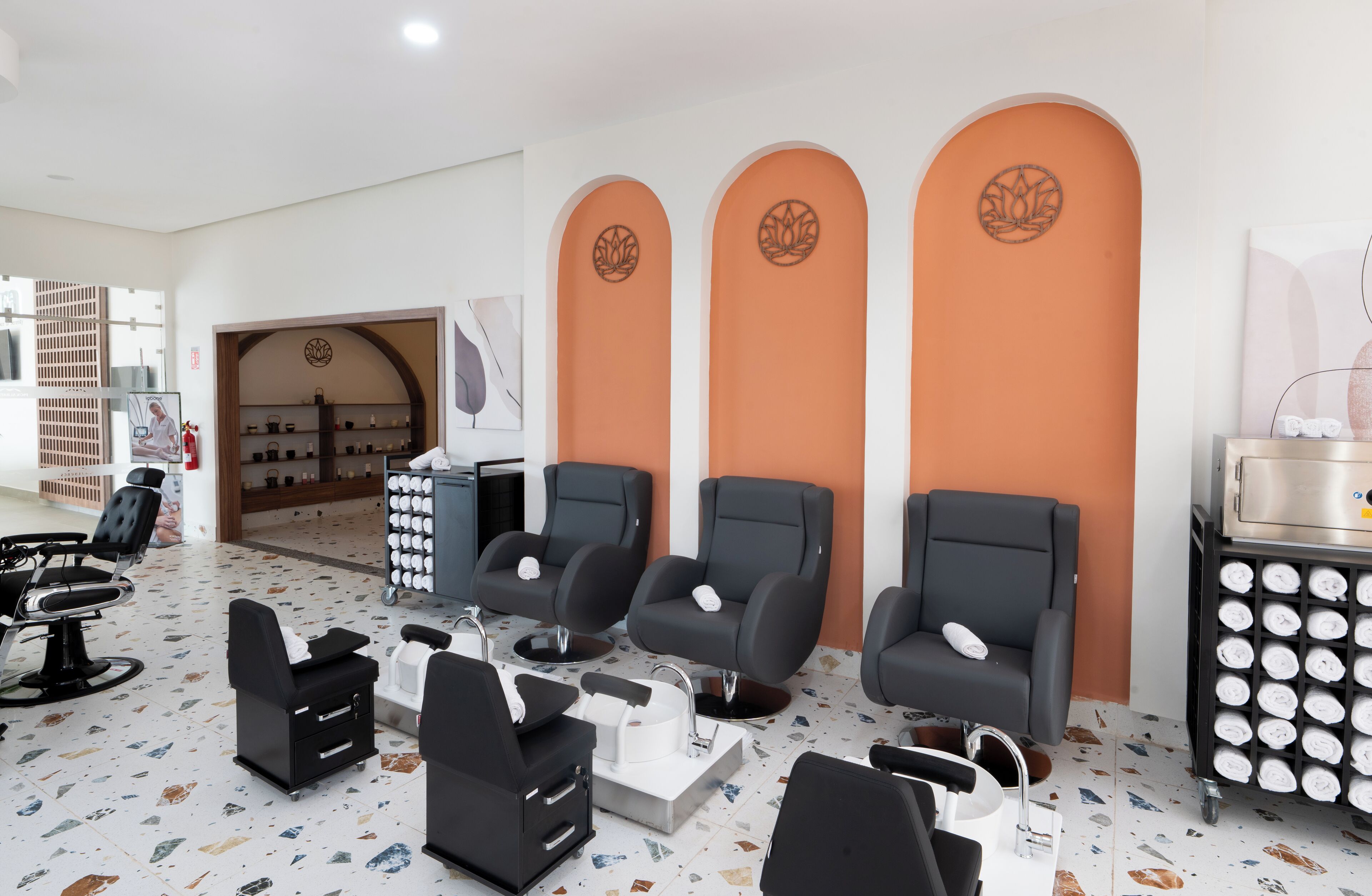 A salon with multiple black chairs, a reception area, and a wall with three arches.