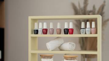 Una mesita de tocador con esmaltes de uñas, una toalla enrollada y frascos de discos de algodón.