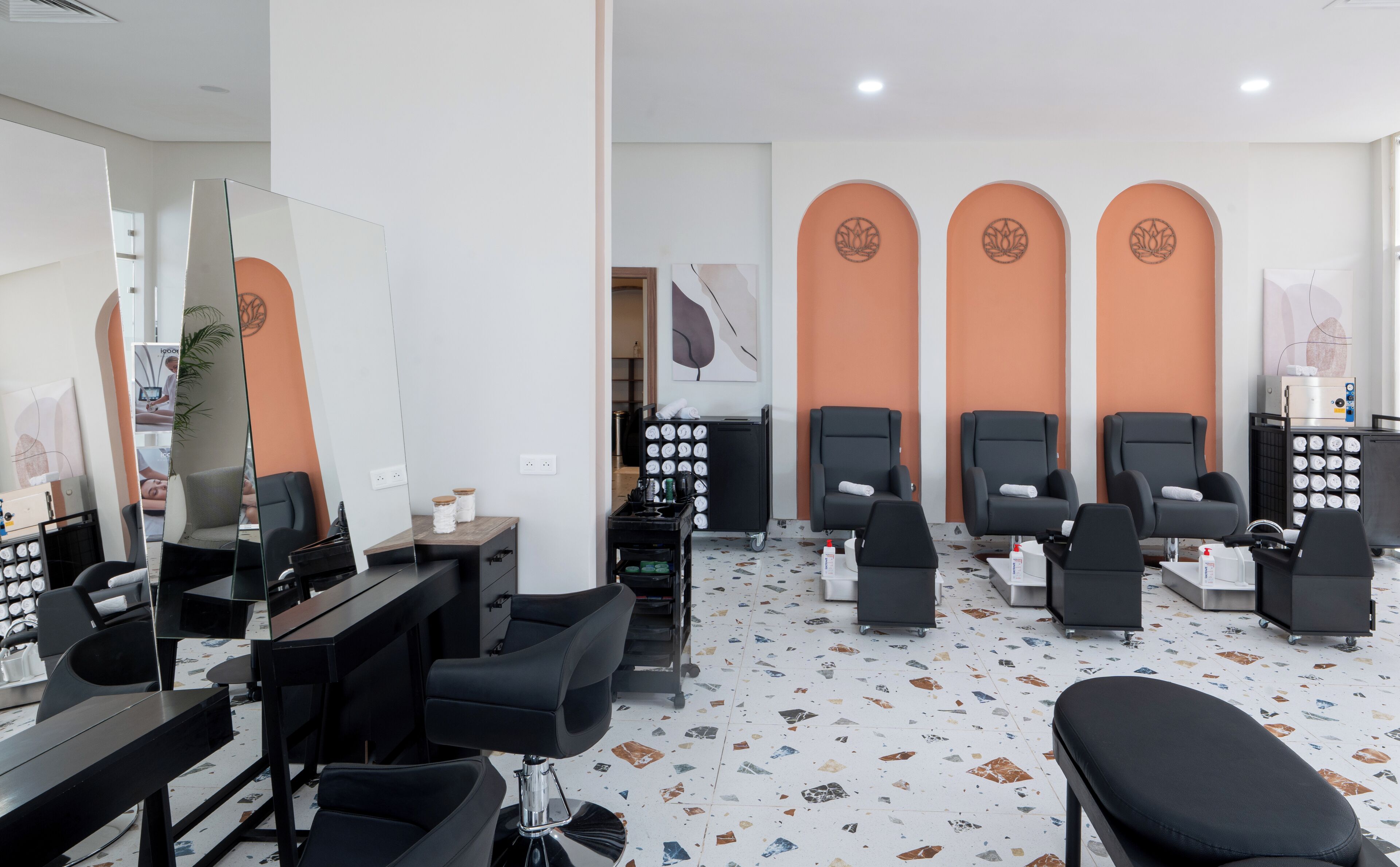 Un moderno cuarto de spa con varias sillas negras, un espejo grande y diversos equipos de spa.