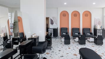 Un moderno cuarto de spa con varias sillas negras, un espejo grande y diversos equipos de spa.