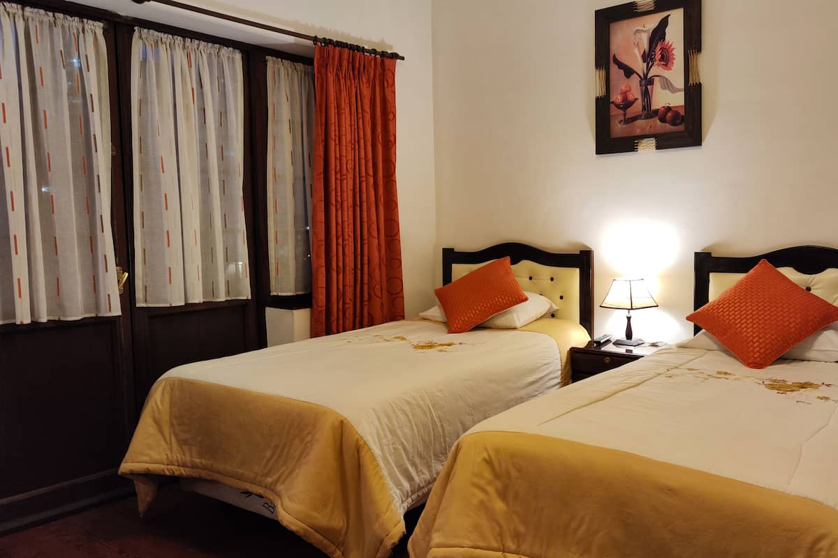 Une chambre d’hôtel avec deux lits, chacun doté d’une tête de lit, d’une table de chevet avec une lampe et d’un tableau au mur.