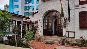 A building with a white facade, a wooden door, and a red-tiled roof. - Maison de la Bolivie Hotel Boutique (La Paz)
