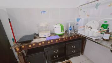 Una cocina con una encimera, una cocedora de arroz, un tostador, un hervidor, un escurreplatos y una botella de jabón para manos.